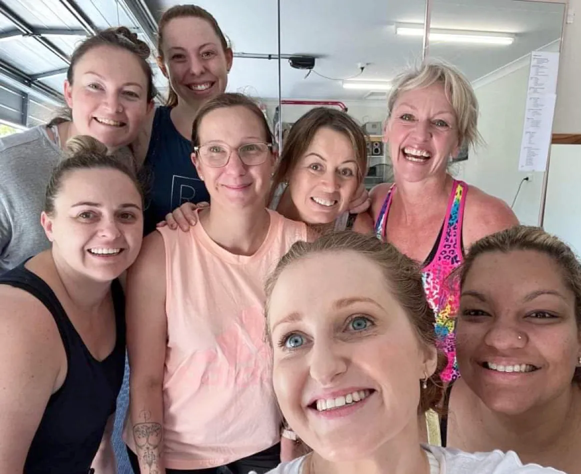 Debi smiling with a group of students after class