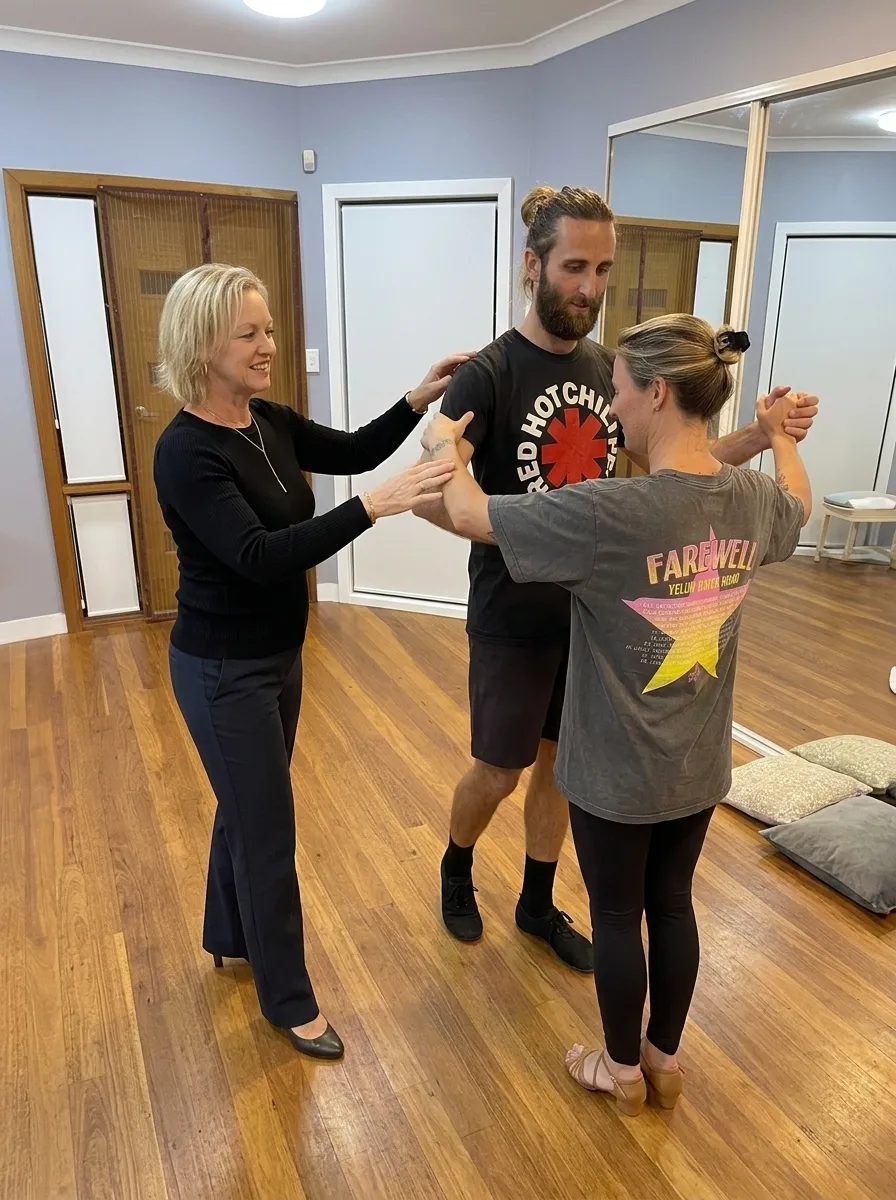 Debi guiding a couple through a dance step in her warm, wooden-floored studio